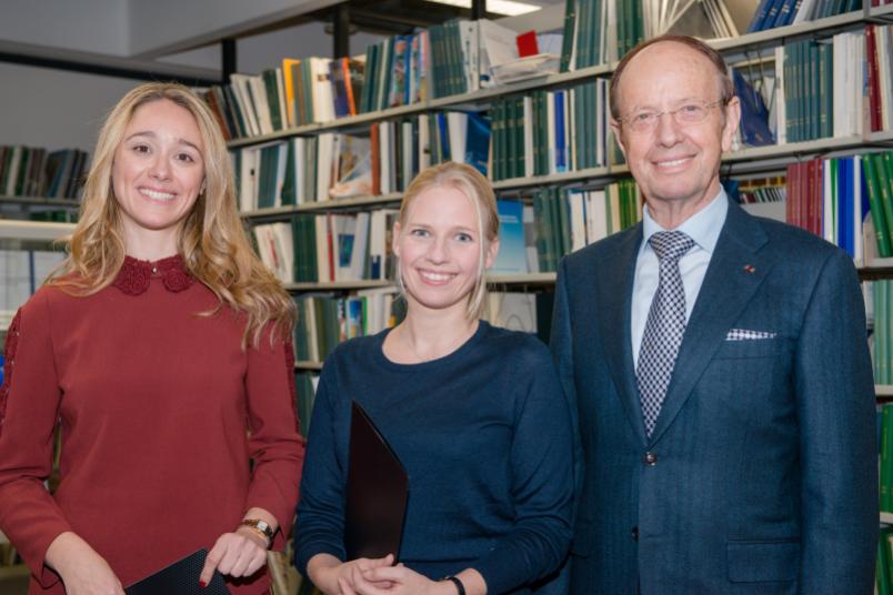 Zwei junge Wissenschaftlerinnen und ein Mann vor einem Bücherregal.