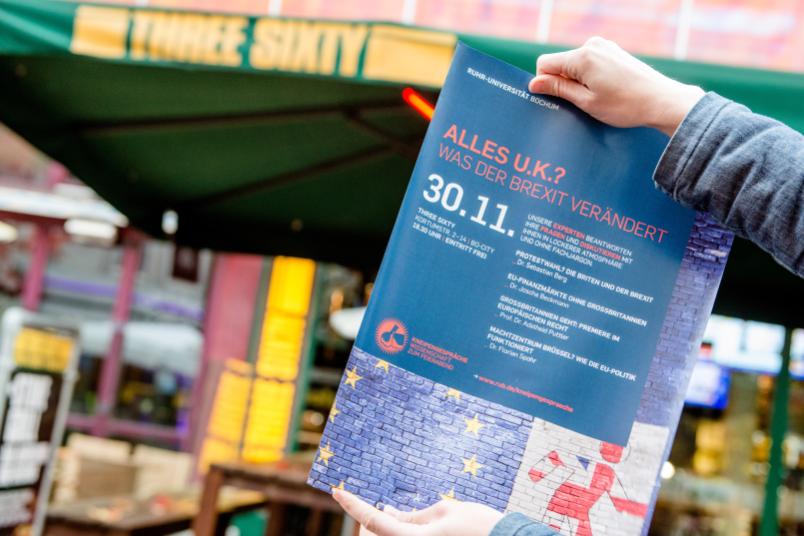 Plakat wird vor einer Bar hochgehalten.