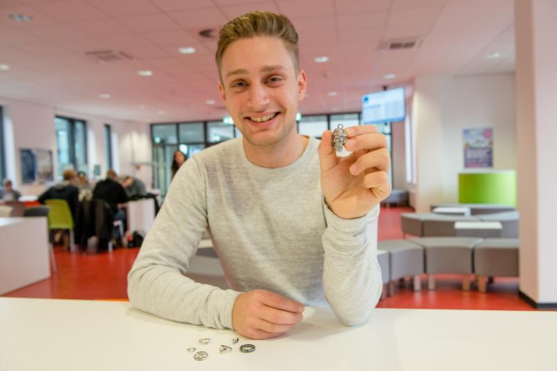 Student hält einen silbernen Totenkopfanhänger in die Kamera.