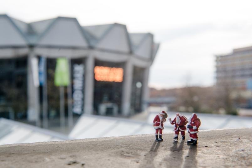 Drei kleine Weihnachtsmannfiguren und das Audimax im Hintergrund