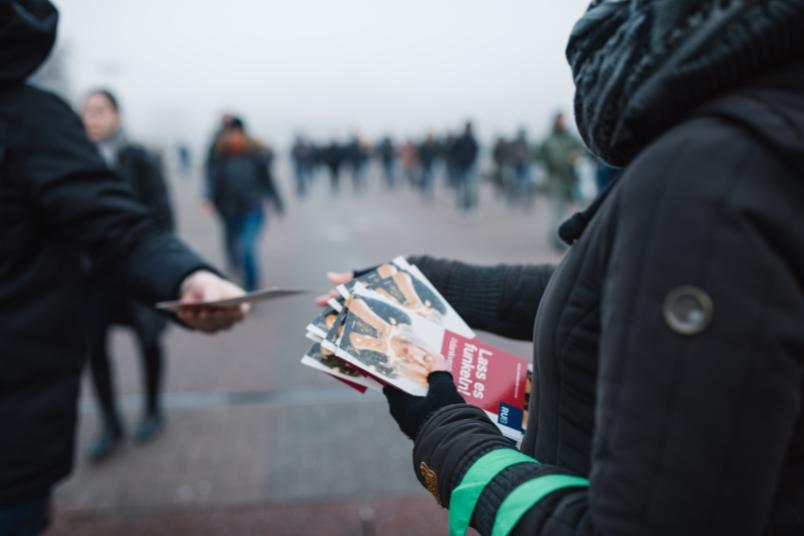 Nahaufnahme von Händen, die Flyer verteilen.