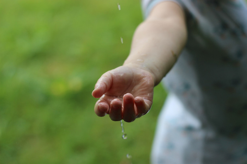 Eine Kinderhand unter tropfendem Wasser