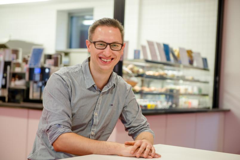 Porträt eines jungen Mannes am Tisch in einer Cafeteria