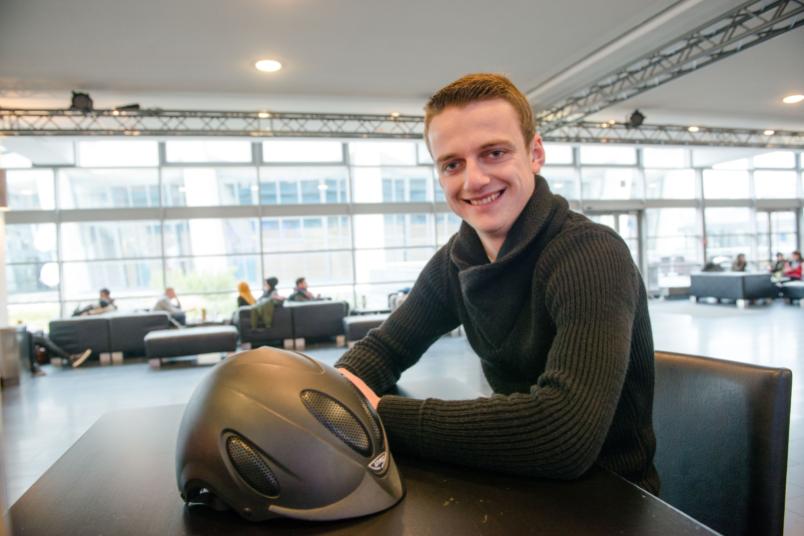 Ein junger Mann sitzt in der Kaffeebar. Auf dem Tisch vor ihm liegt ein Reithelm.