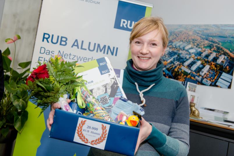 Porträt einer etwa 40-jährigen Frau mit Blumen und Geschenken in der Hand