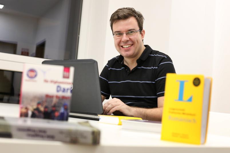 Student sitzt mit Wörterbüchern am Laptop.