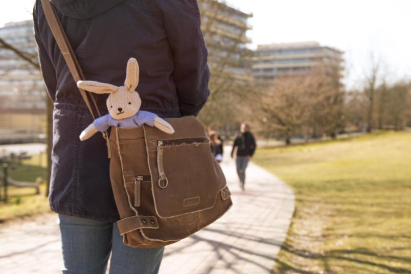 Studentin von hinten, offenbar auf dem Weg zur Vorlesung, aus ihrer Tasche lugt ein Stoffhase hervor