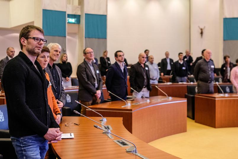 In einem Plenum stehen Menschen.