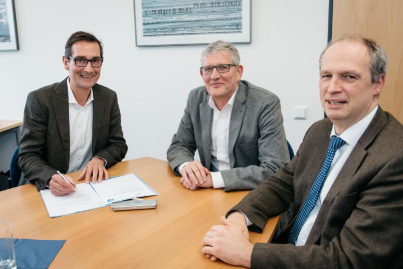 Drei Männer sitzen an einem Tisch.