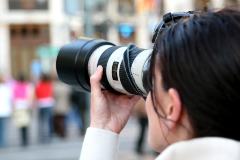 Frau mit Fotoapparat und langem Objektiv
