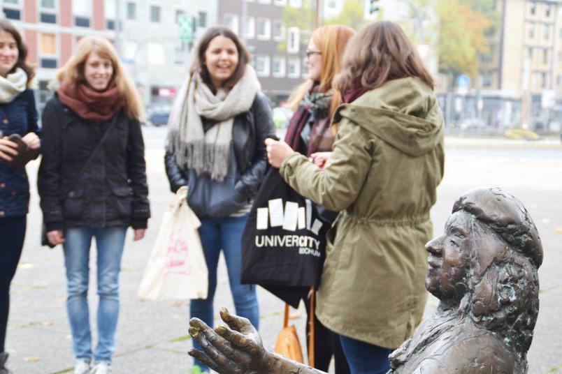 Junge Menschen stehen neben einer Statue zusammen