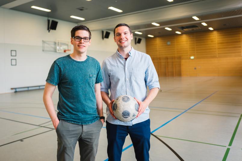 Zwei junge Männer mit Fußball in einer Sporthalle