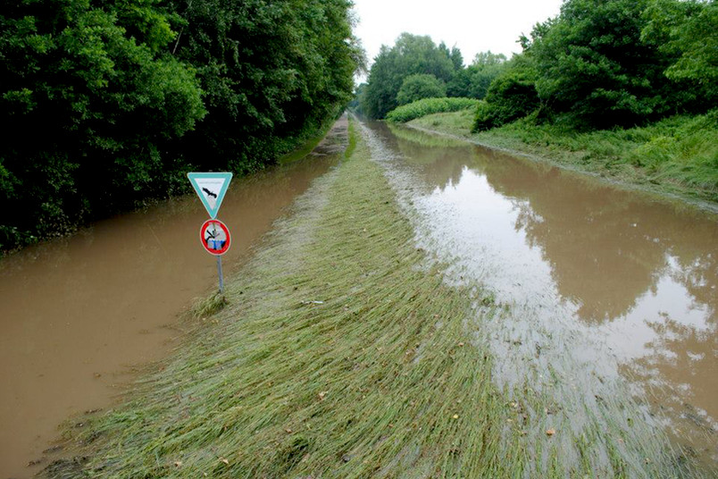 Überschwemmter Radweg neben einem Bach