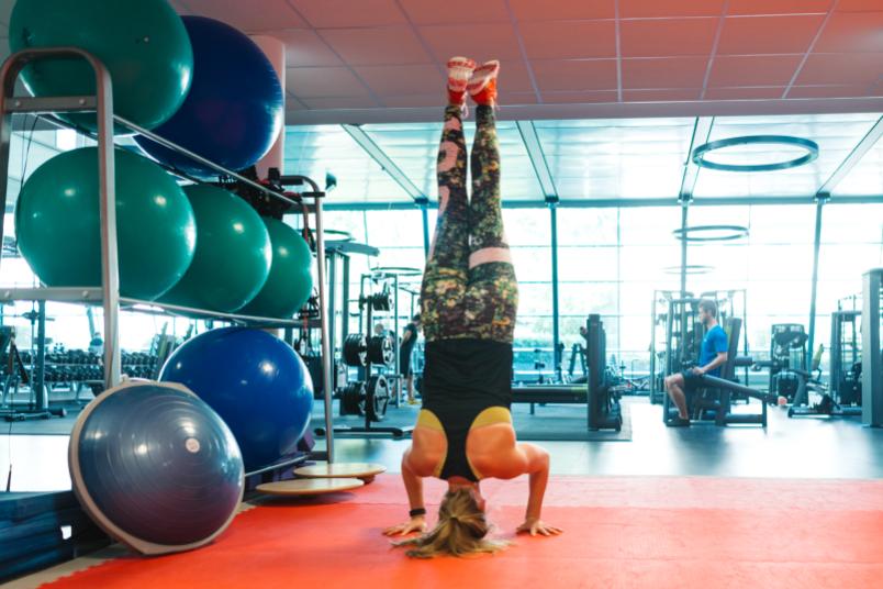 Eine Frau macht in einem Fitnessstudio einen Kopfstand