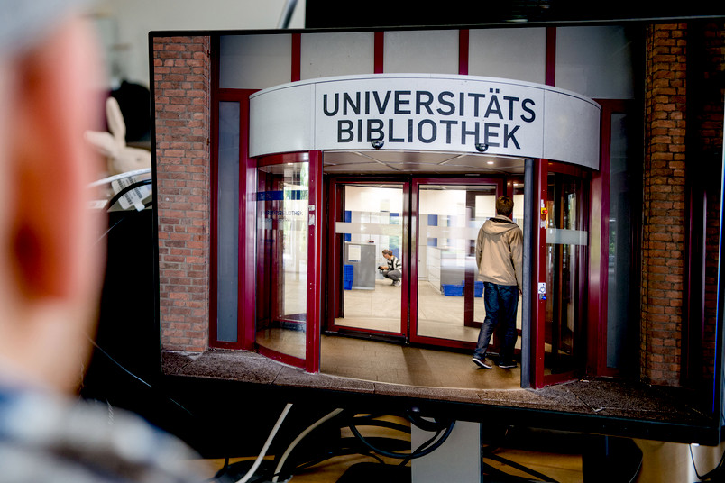 Fotomontage mit dem Eingang der Unibibliothek auf einem Bildschirm