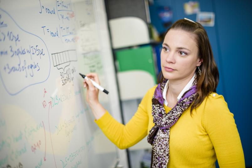 Frau schreibt Formeln an ein Whiteboard.