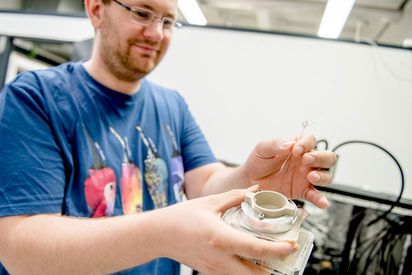 Ein Forscher hält eine hauchdünne Elektrode in den Händen.