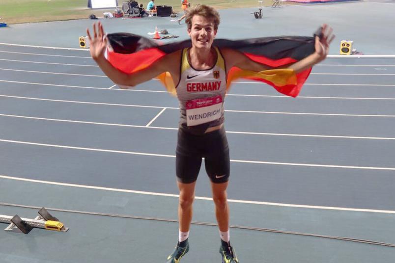 Ein Athlet spingt jubelnd in die Höhe und hält die Deutschlandfahne in die Höhe.