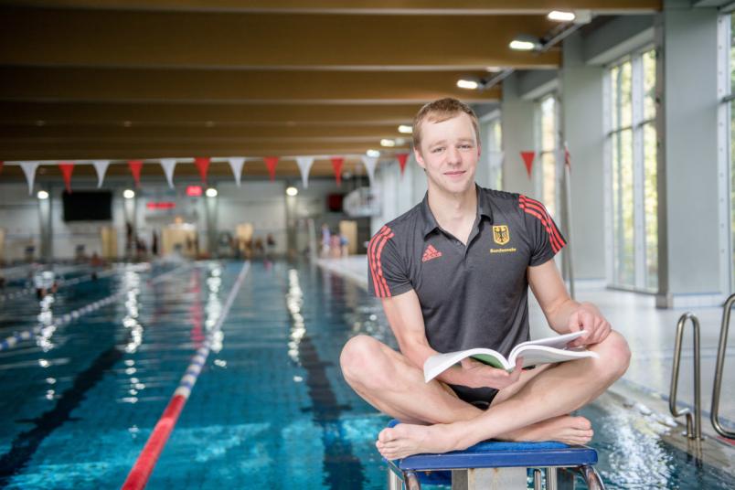 Student sitzt am Schwimmbecken.