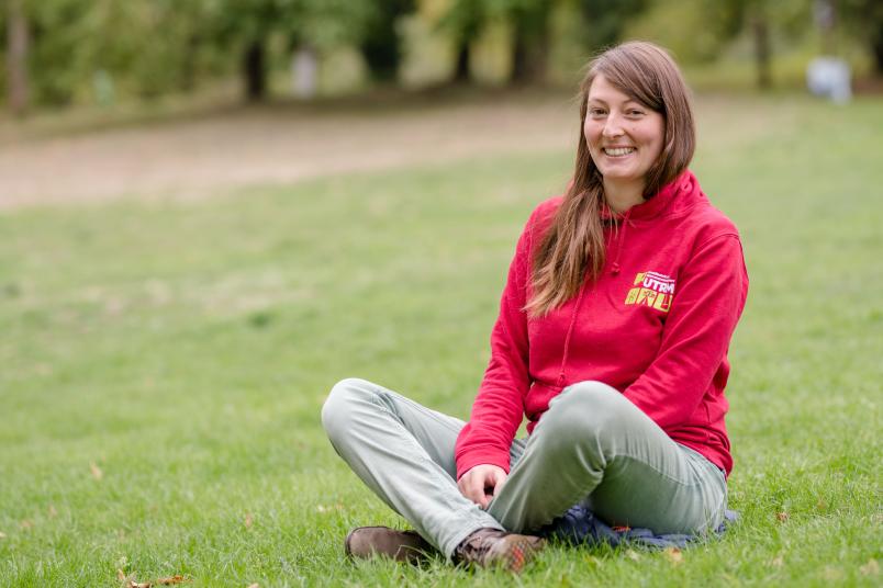 Studentin sitzt auf Wiese.