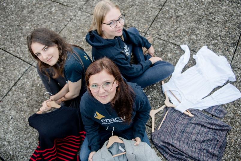 Drei Studentinnen sitzen auf dem Boden. 
