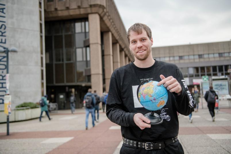 Student mit Weltkugel in der Hand. 