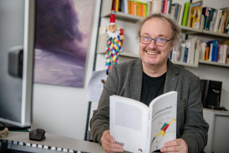Theaterwissenschaftler mit Buch am Schreibtisch