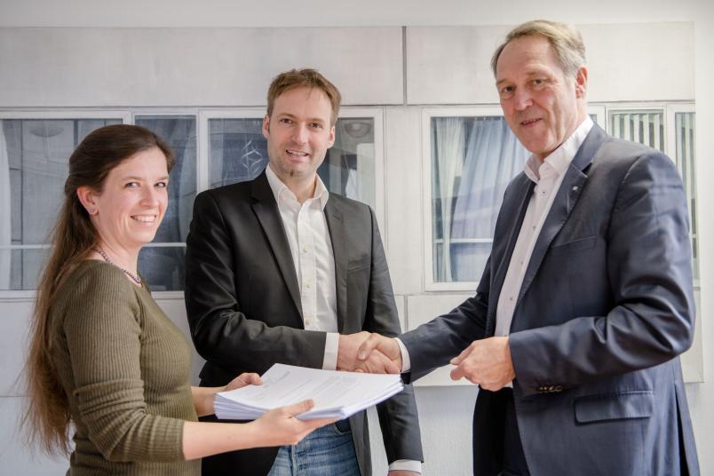 Eva und Tobias Glasmachers überreichen Rektor Axel Schölmerich die gesammelten Unterschriften (von links).