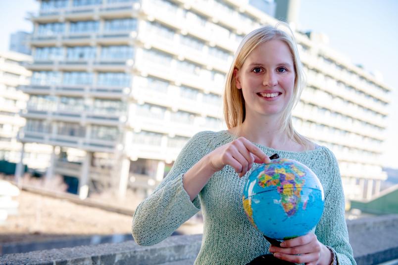 Studentin mit Globus vor RUB-Kulisse
