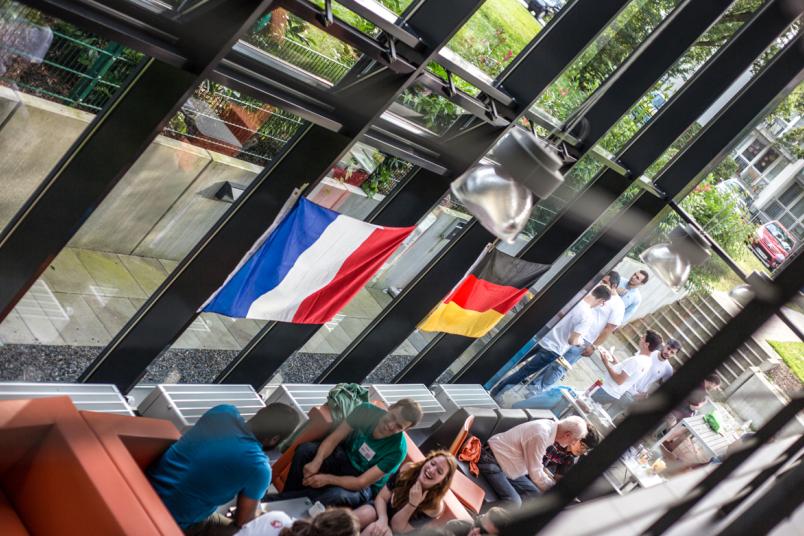 Studierende an Tischen, an der Fensterfront die deutsche und die französische Flagge