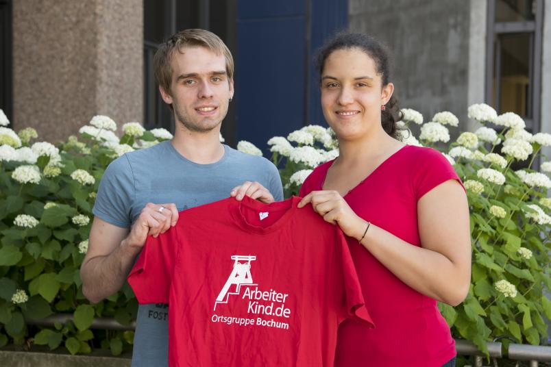 Studentin und Student halten rotes T-Shirt hoch