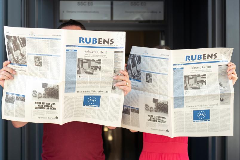 Zwei Personen halten je eine Zeitung