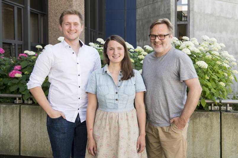 Student, Wissenschaftlerin und Professor stehen nebeneinander. 