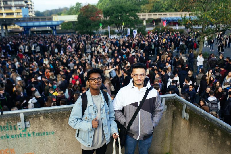 Zwei junge Männer stehen oberhalb einer Menschenmenge