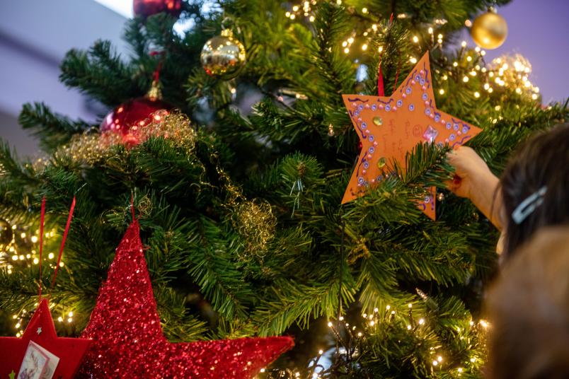 Kind hängt Wunschstern an Weihnachtsbaum