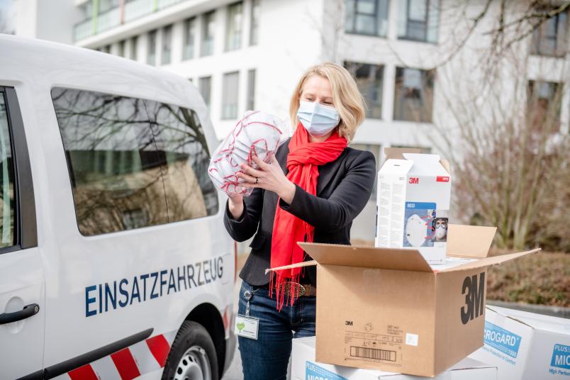 Dr. Irmgard Plößl, Leiterin Einkauf und Apotheke, nimmt am St. Josef-Hospital die Schutzmaterialien aus der RUB entgegen.