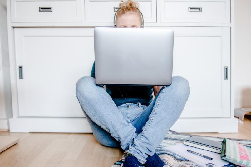 Studentin sitzt mit Laptop auf dem Boden. 