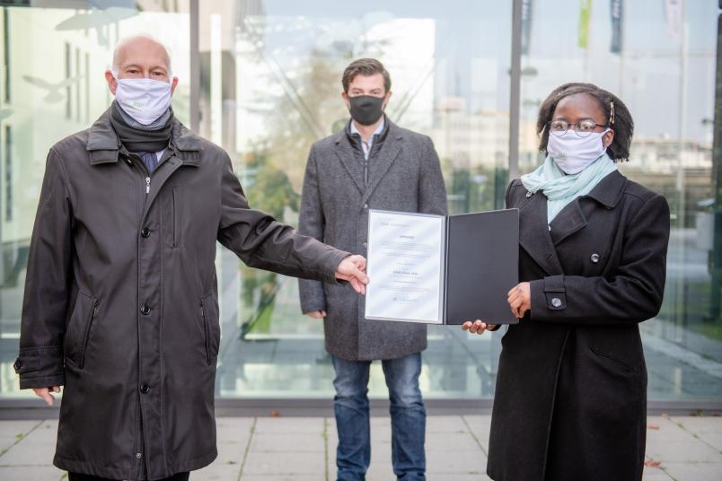 Übergabe einer Urkunde. Personen von links nach rechts: Elmar Weiler, Christoph Baer, Ngole Noumegne.
