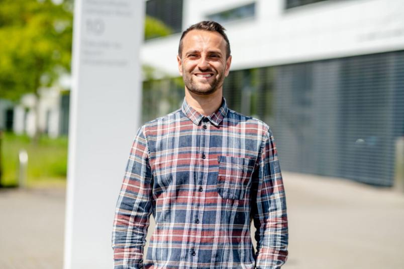 Ein Mann im Karohemd steht in der Sonne und lacht