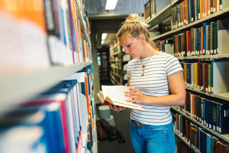 Studentin zwischen Bücherregalen