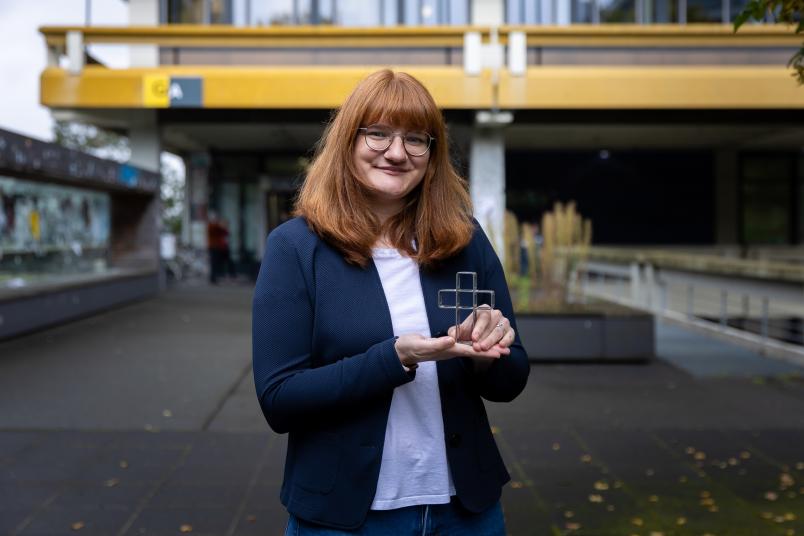 Person mit einem kleinen Kreuz in der Hand