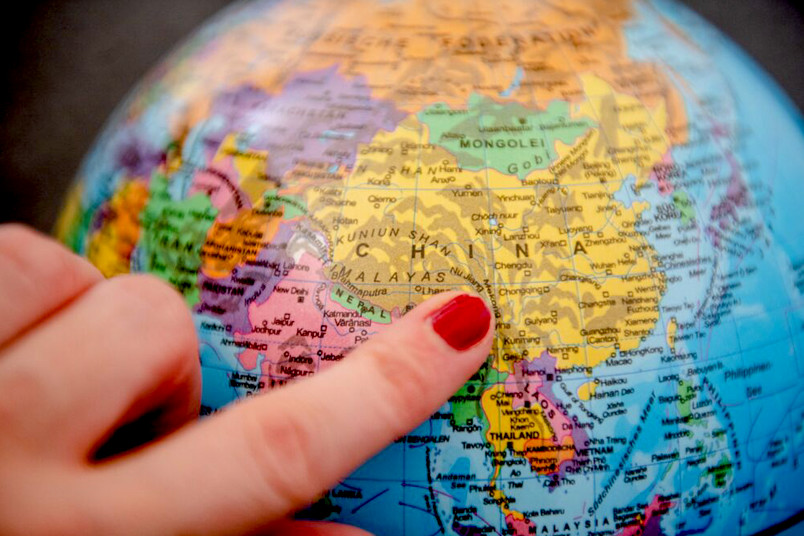 Finger deutet auf Globus auf China