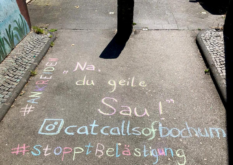 In bunter Schrift steht auf dem Boden geschrieben &quot;#Ankreiden&quot;, &quot;Na, du geile Sau!&quot;, &quot;@catcallsofbochum&quot; und &quot;StopptBelästigung&quot;