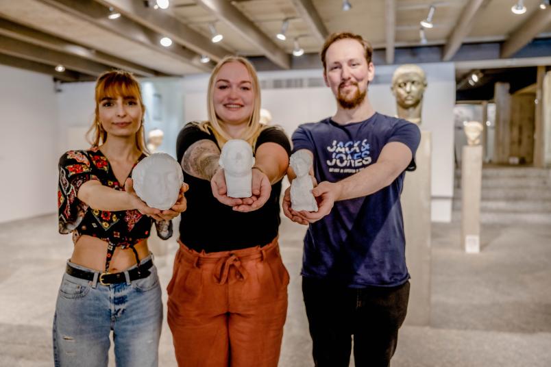 Drei Studierende mit Büsten aus 3D-Druckverfahren in den Händen.