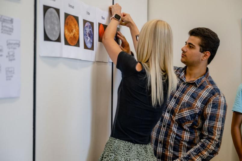 Studentin und Schüler stehen an einer Wand. 