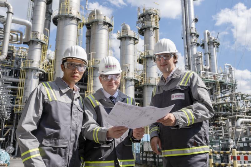 Drei Personen vor einer industriellen Anlage