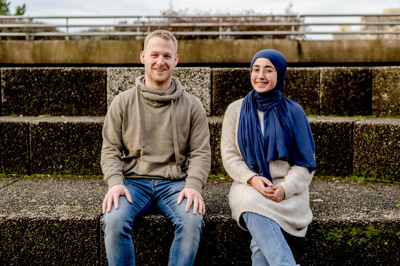 Talentscout Christian Maihöfer sitzt auf einer Treppe zusammen mit der Schülerin Wina Ismail. 