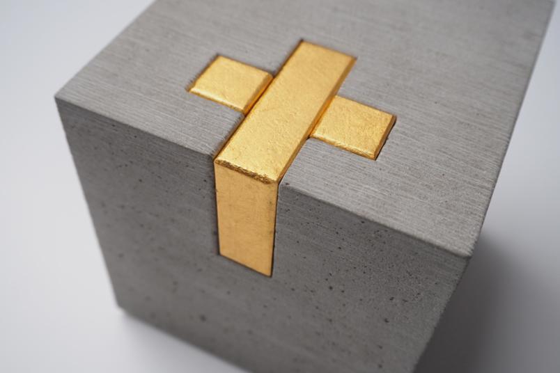 Kunstwerk: Betonquarder mit vergoldetem Holzkreuz