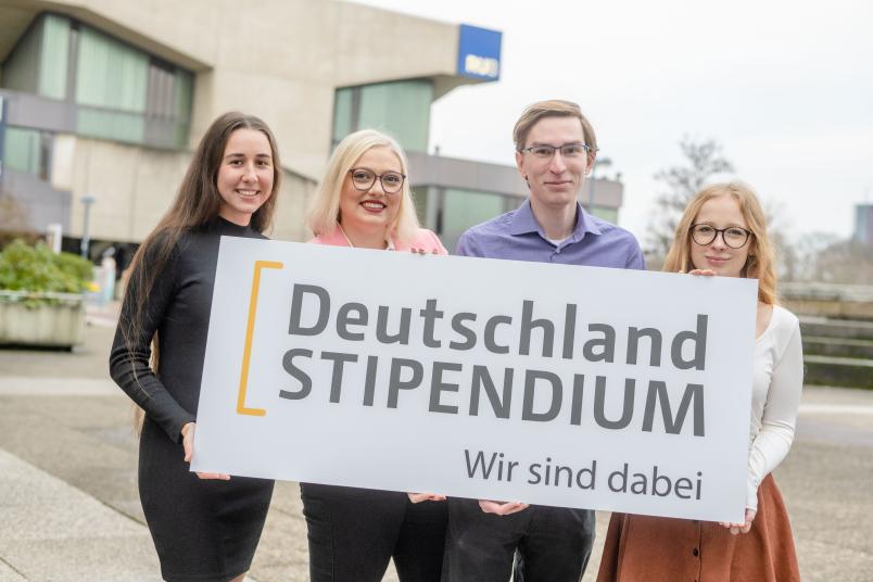 Vier Studierende halten ein Schild.