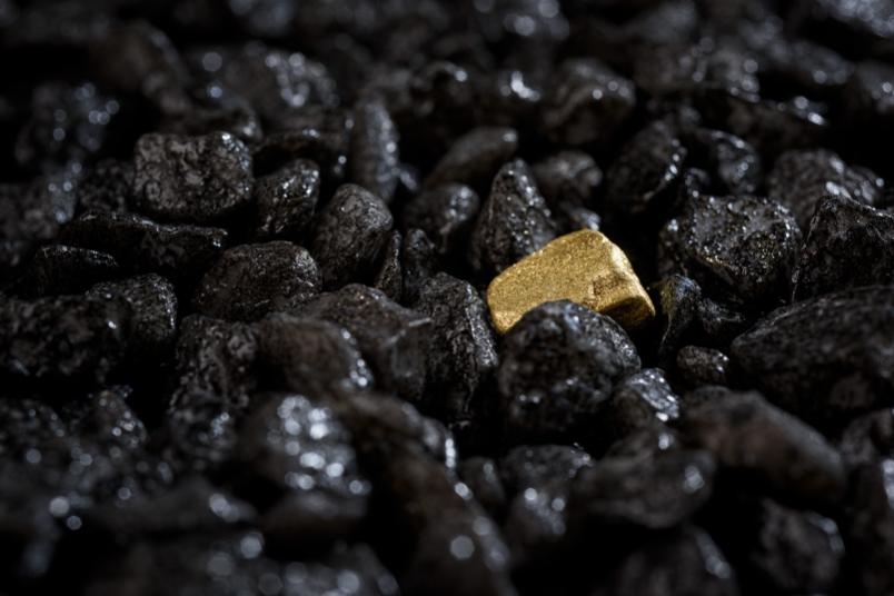 Goldener Stein zwischen vielen schwarzen Steinen